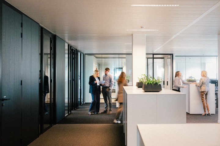 Groep collega’s die overleggen en werken in een lichte, moderne kantooromgeving.